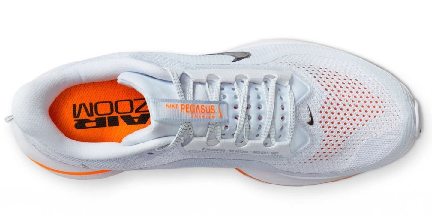 Top view of Nike Pegasus Premium running shoe in white with orange Air Zoom insole and black Swoosh logo