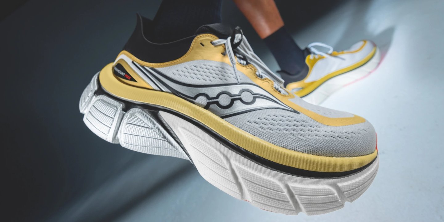 Saucony Paramount Max running shoe in yellow, white and grey with chunky midsole, shown mid-air from a side angle.