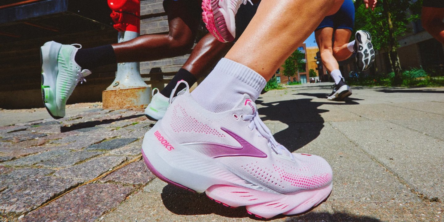 Close-up of a woman's foot in a Brooks Glycerin running shoe in white and pink on a cobblestone street