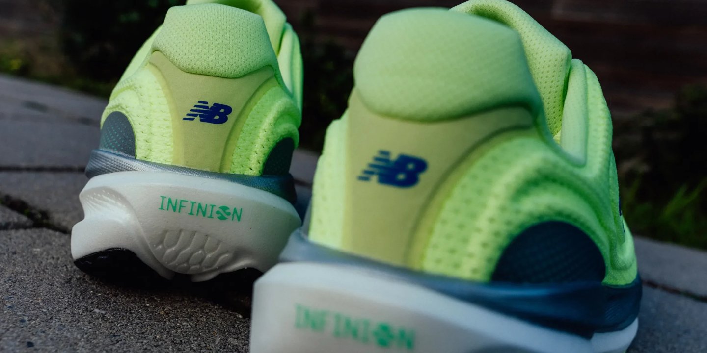 Heel view of New Balance Infinion running shoes in neon lime green with NB logo and Infinion midsole branding.