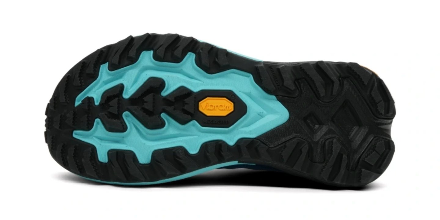 Bottom view of Hoka trail running shoe with teal and black Vibram Megagrip outsole and aggressive lug pattern