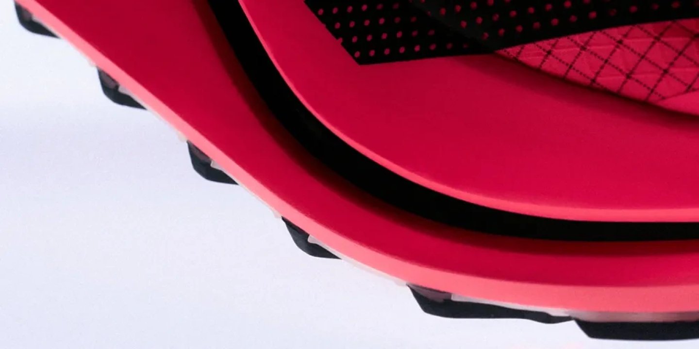 Close-up detail of the Adidas Terrex Agravic Evo trail running shoe showing red midsole layers and black rubber outsole lugs.