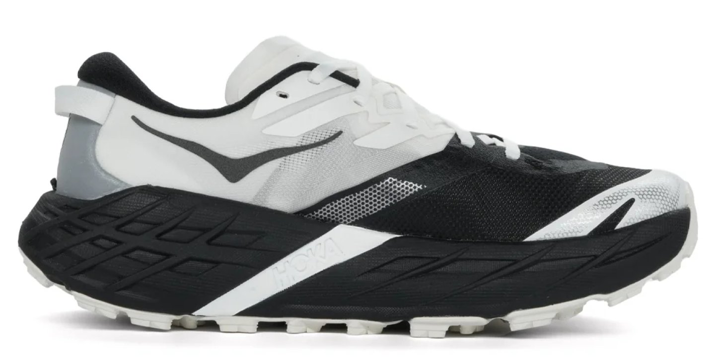 Hoka trail running shoe in black and white with maximalist cushioned midsole and lugged outsole, lateral view.
