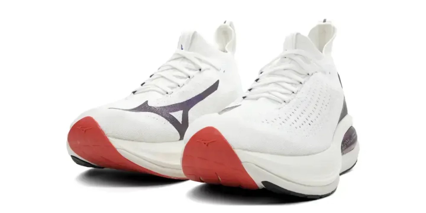 Pair of Mizuno white knit running shoes with purple logo and red rubber outsole, angled three-quarter view.