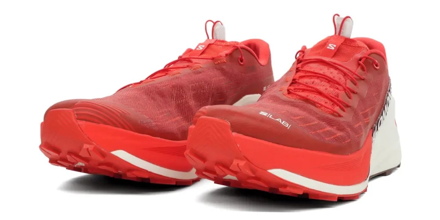 Pair of Salomon S/LAB trail running shoes in red and white with aggressive outsole lugs, shown at an angle.
