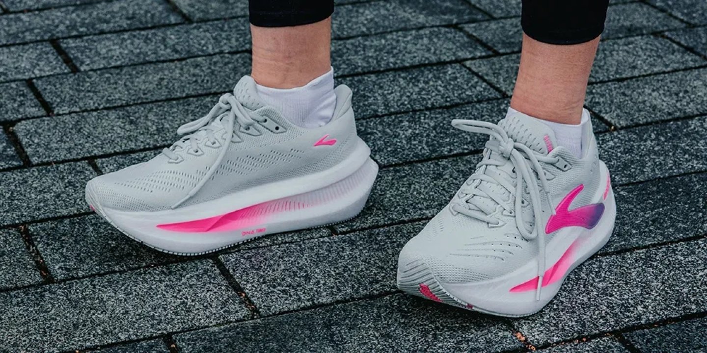 Woman wearing Brooks Glycerin 21 running shoes in grey with pink DNA LOFT midsole accents on cobblestone surface