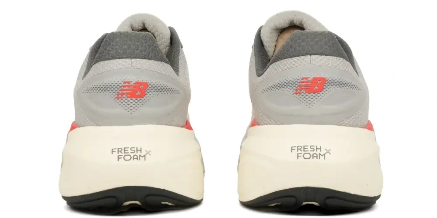 Rear view of New Balance Fresh Foam X running shoes in grey with red accents and cream midsole, showing NB logo